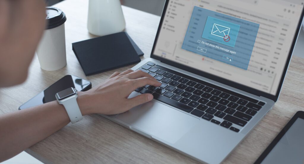 A person using a laptop with a suspicious email warning on screen, illustrating phishing checks after a suspected data leak.