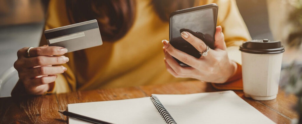A person holding a payment card and smartphone, illustrating the need to secure payment details after a suspected personal data leak.